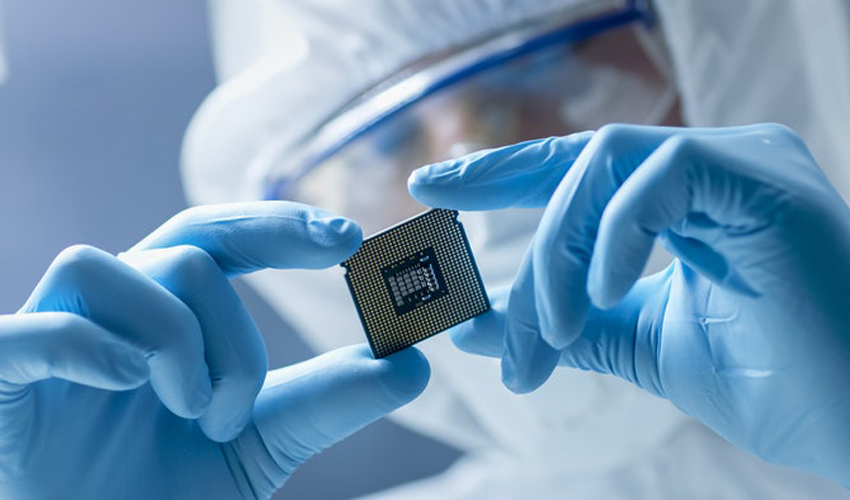 lab technician wearing gloves and handling a semiconductor chip