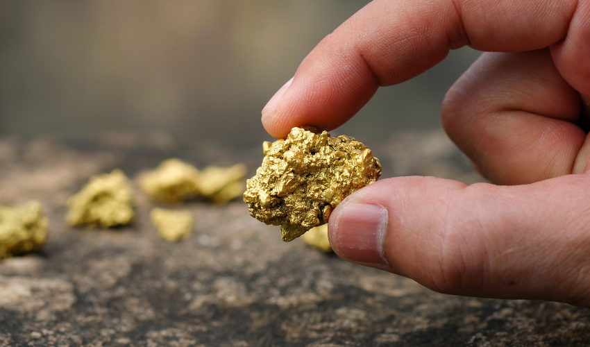 person holding a piece of gold mineral
