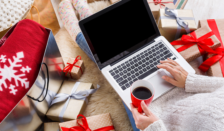 Christmas online shopping above view. Female buyer makes order on laptop, copy space on screen. Woman buy presents, prepare to xmas, among gift boxes and packages. Winter holidays sales